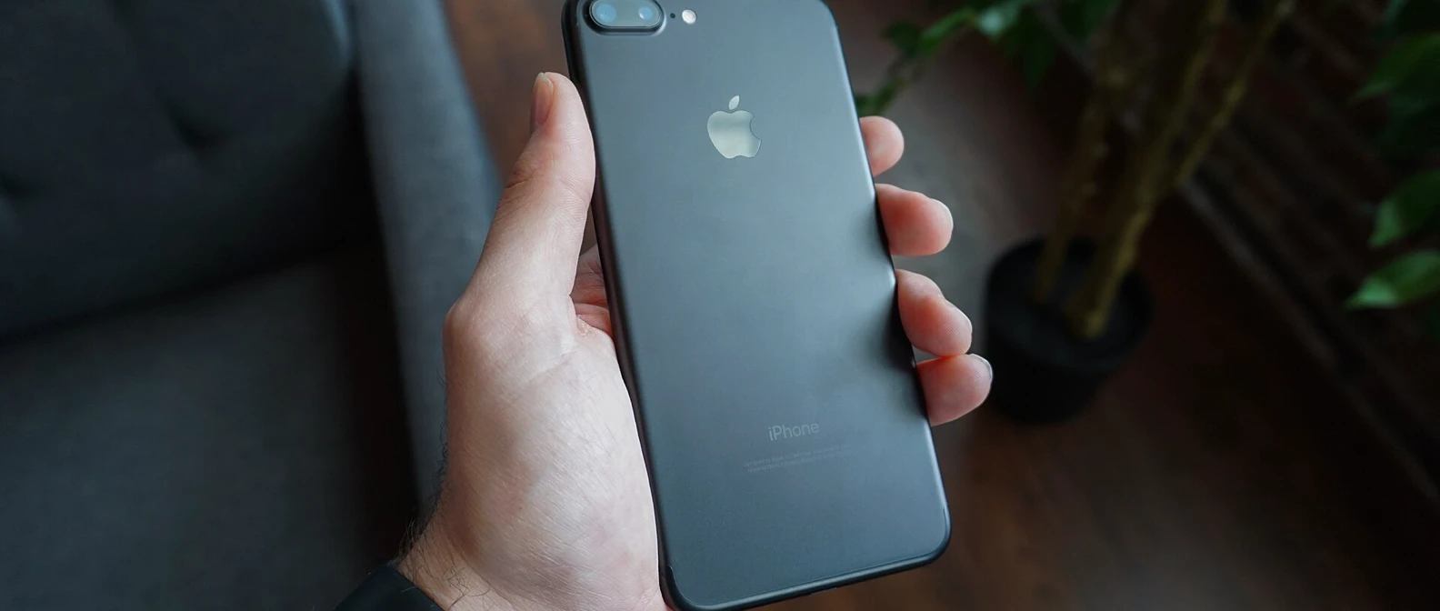 A hand holding a black iPhone, the phone you check first for shared logins, spy apps and call forwarding