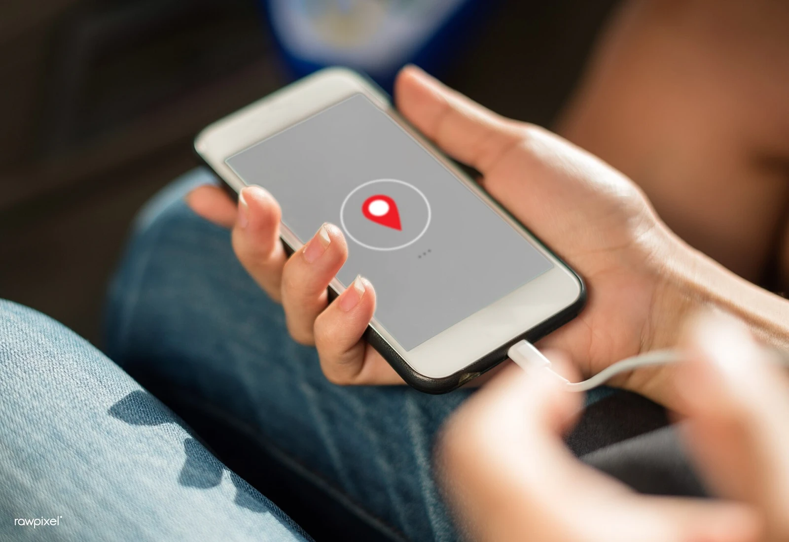 Two hands holding a smartphone with a location pin on the screen, the kind of location sharing that someone signed in to your account can see